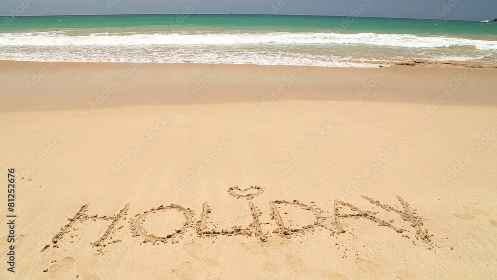 Ocean wave approaching word holiday written in sand on beach Ocean wave approaching word holiday written in sand on beach