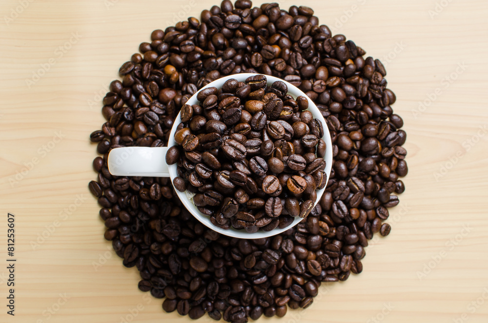 Fototapeta premium Roasted brown coffee beans & mug on wooden table