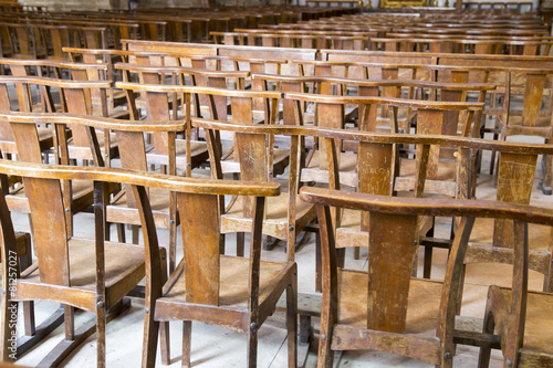 Rows of many worn wooden chairs in a church