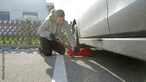 woman lifting car with jack to change tires
 photo