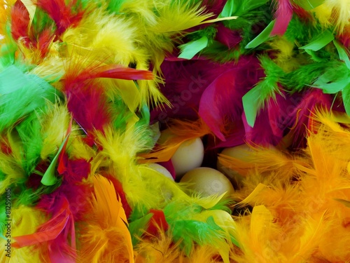 Easter eggs in a basket with colorful feathers