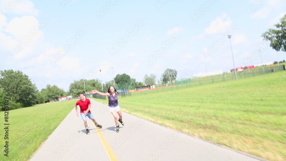 Happy young couple rollerblading on a wonderful sunny day in park, holding each other Happy young couple rollerblading on a wonderful sunny day in park, holding each other