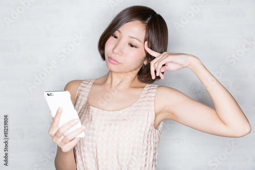 スマホを見て考え込む女性