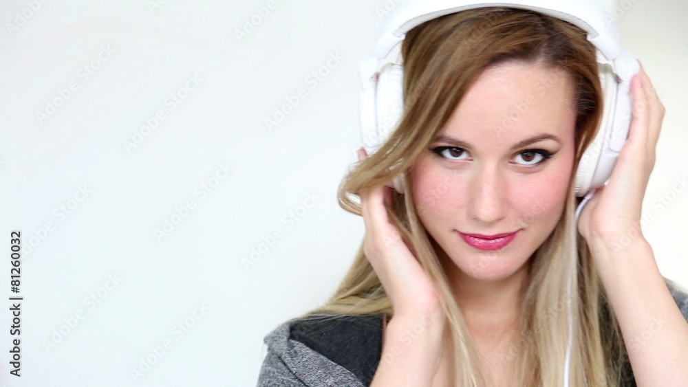 Beautiful young blond woman dancing with white headphones in white bright background Beautiful young blond woman dancing with white headphones in white bright background