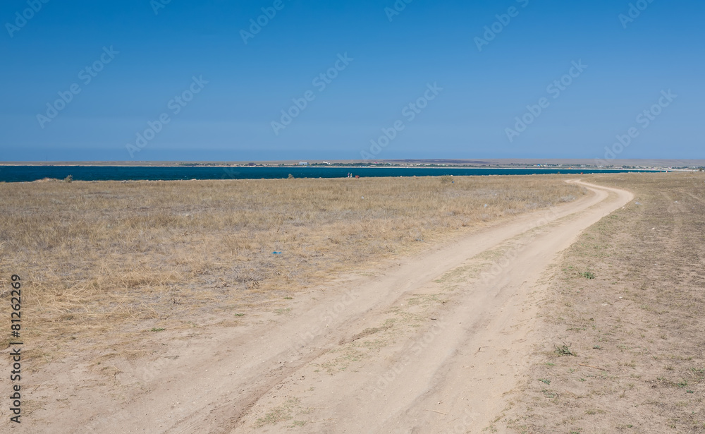 Road through the field next to sea. Road through the field next to sea.