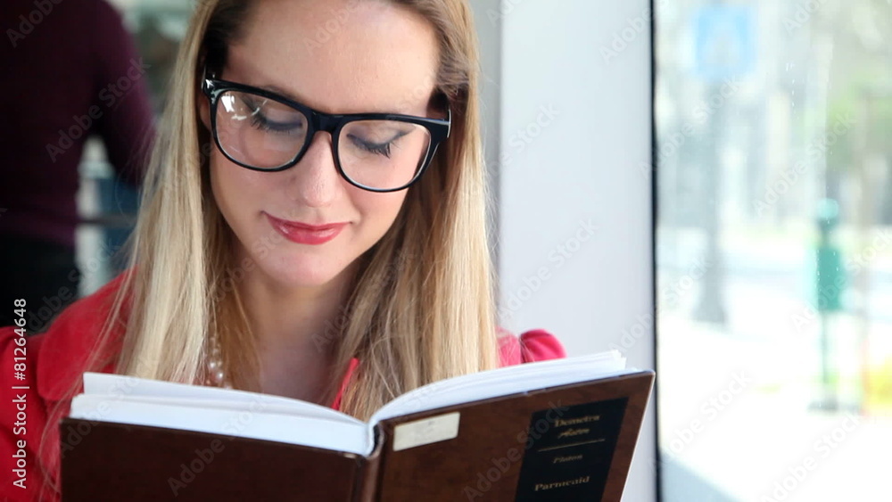Beautiful blond young woman reading book sitting in tram, looking at camera Beautiful blond young woman reading book sitting in tram, looking at camera