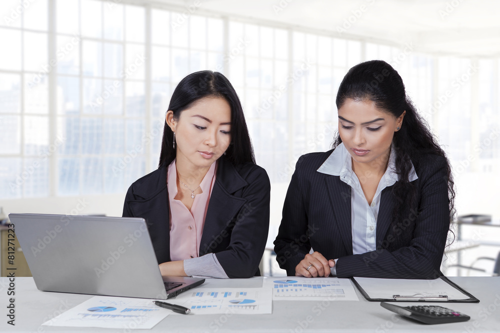 Two employees with paperwork in office Two employees with paperwork in office
