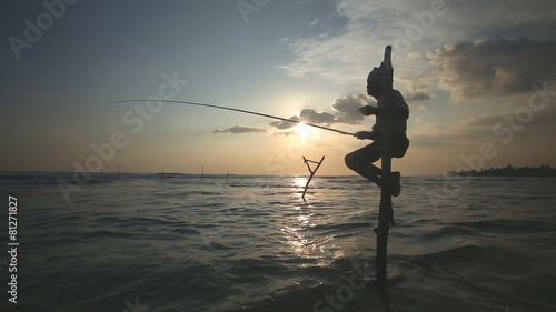 GALLE, SRI LANKA - MARCH 2014: Silhouette of elderly fisherman on a fishing pole at sunset. Stilt fishing is a tradition that only 500 fishing families of Galle practice.