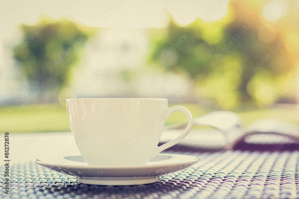 Obraz premium Coffee cup with book on the table in blurred nature background