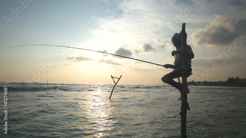 GALLE, SRI LANKA - MARCH 2014: Silhouette of elderly fisherman on a fishing pole at sunset. Stilt fishing is a tradition that only 500 fishing families of Galle practice.