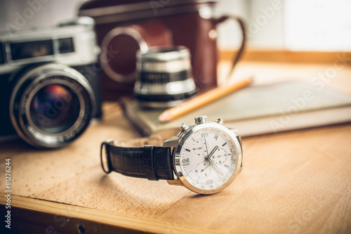 male watches lying on table against photography retro set