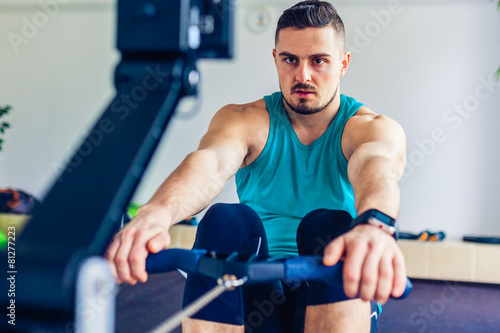 Crossfit instructor at the gym doing Rowing Exercise