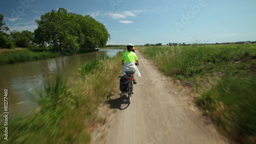 Slow motion - Retired couple cycling beside river on holiday