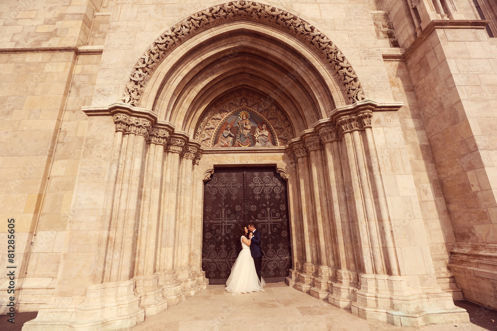 Fototapeta premium Bride and groom embracing in front of the church