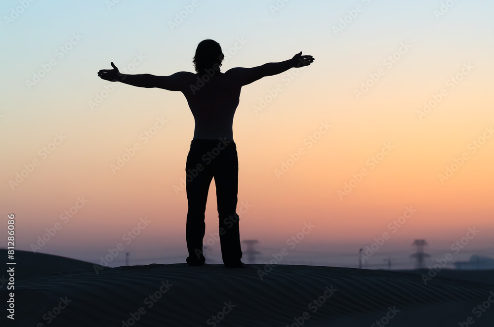 Fototapeta premium The man silhouette alone at sunset with outstretched arms