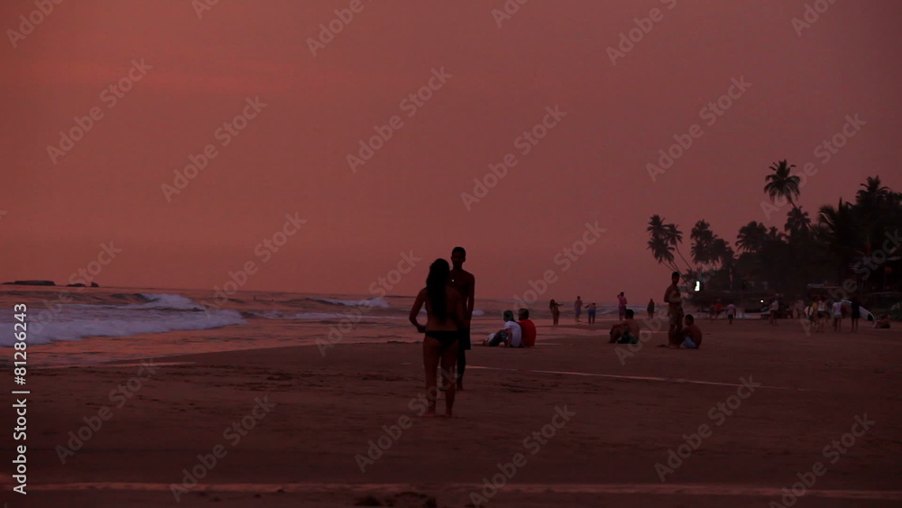 HIKKADUWA, SRI LANKA - FEBRUARY 2014: View of Hikkaduwa beach at sunset, while waves are splashing and people are playing with frisbee. Hikkaduwa is famous for its beaches. HIKKADUWA, SRI LANKA - FEBRUARY 2014: View of Hikkaduwa beach at sunset, while waves are splashing and people are playing with frisbee. Hikkaduwa is famous for its beaches.