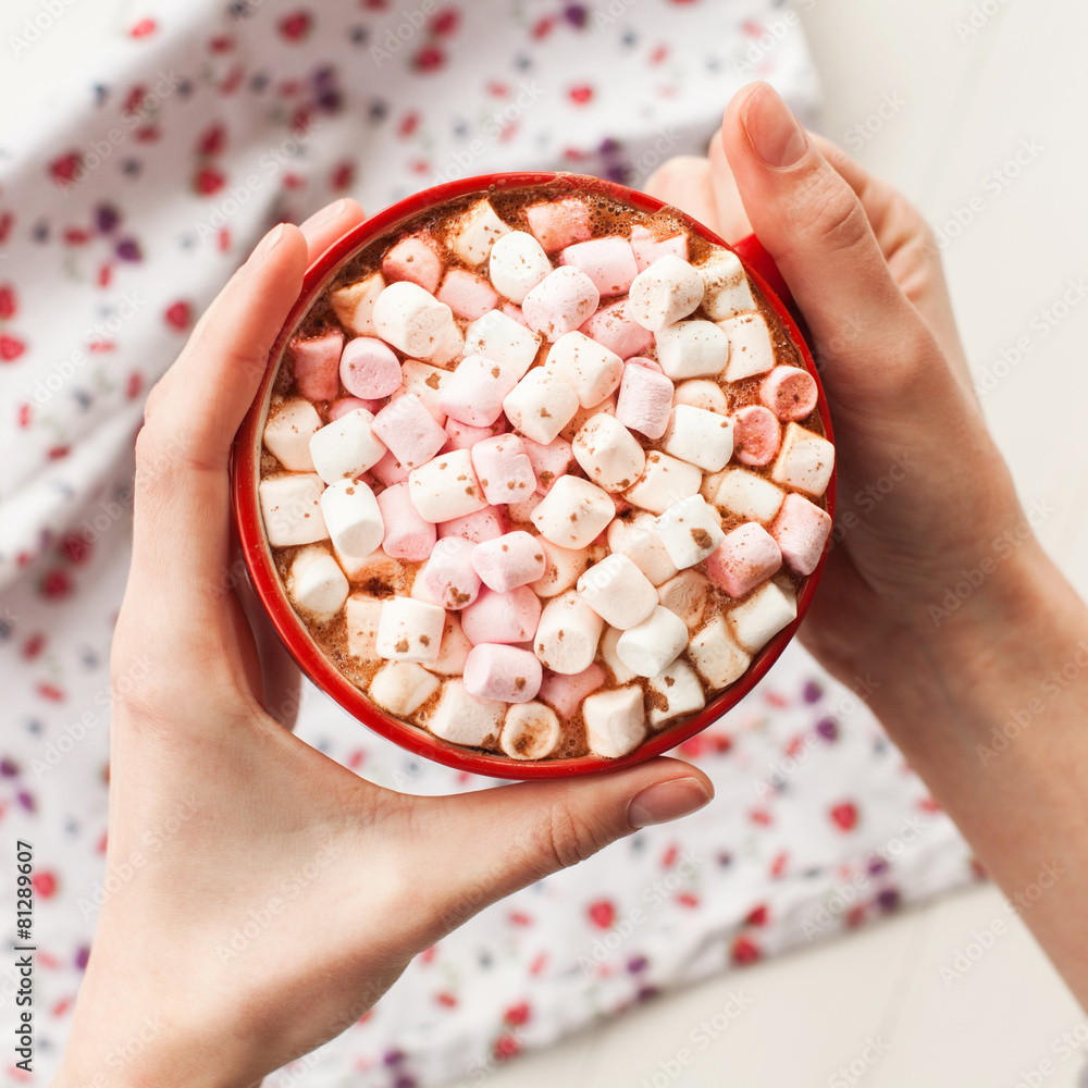 Hands holding hot chocolate with marshmallows in cup Hands holding hot chocolate with marshmallows in cup