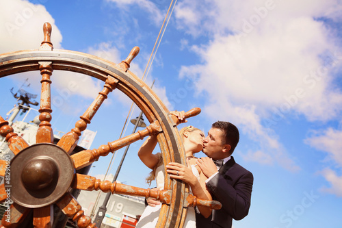 Bride and groom holding old boat steering wheel