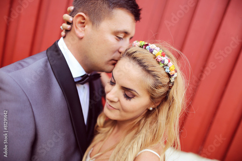 Cheerful bride and groom against red wall © hreniuca