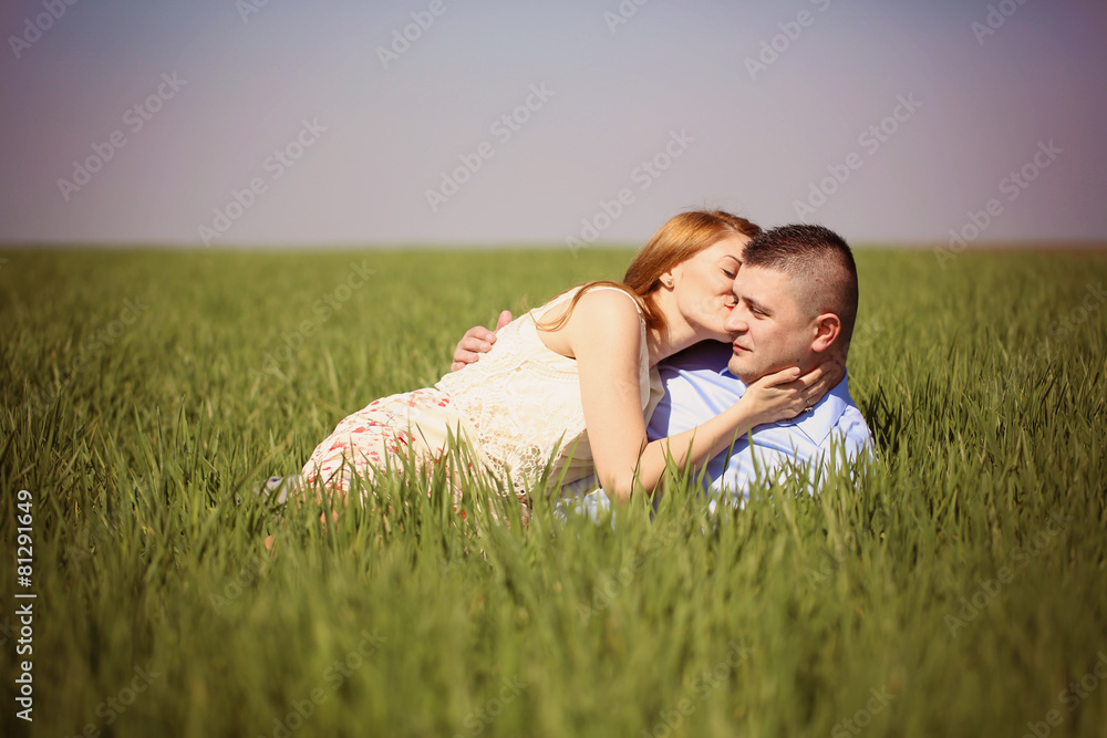 Beautiful cheerful couple laying on green grass Beautiful cheerful couple laying on green grass