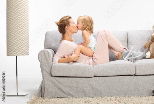 Young beautiful mother playing with daughter in livingroom