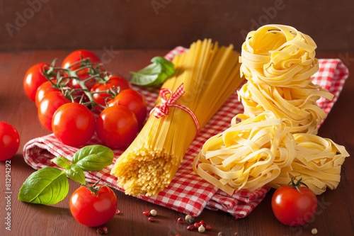 raw spaghetti pasta basil tomatoes. italian cuisine in rustic ki