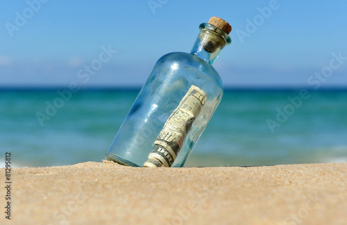 Botella con dólares en la playa solitaria