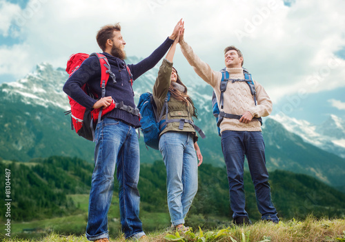 group of smiling friends with backpacks hiking