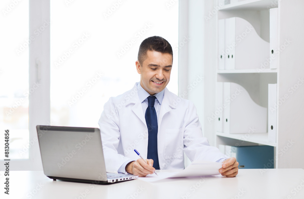 smiling male doctor with laptop in medical office