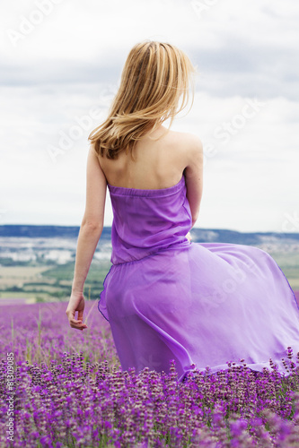 Woman is wearing purple dress relaxing in lavender field