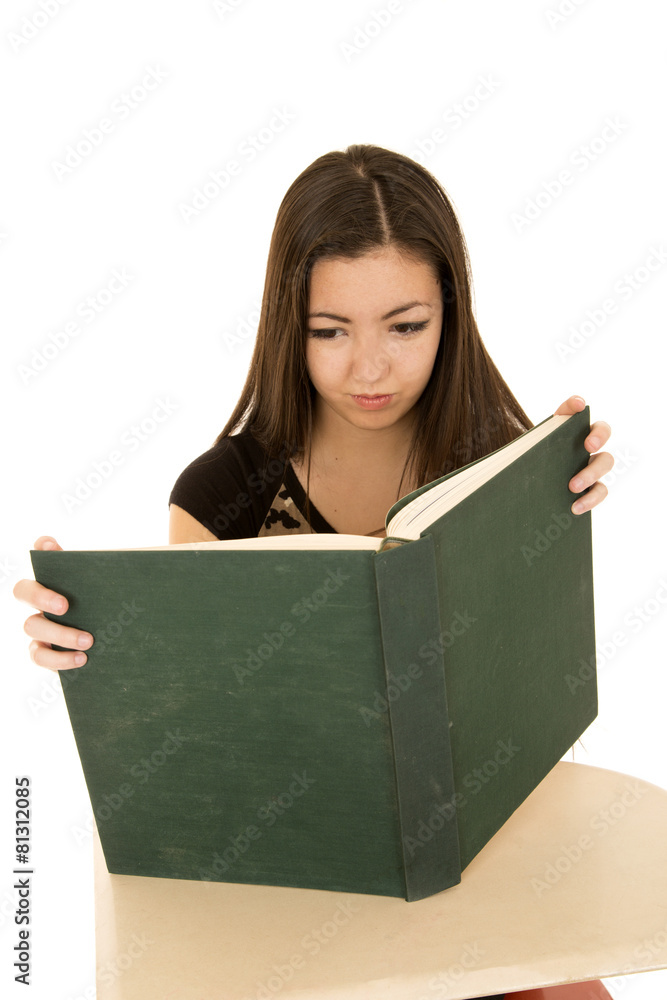 Female student reading a large book at a school desk