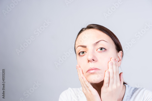 Fotografie Serious Woman Touching her Face with Two Hands