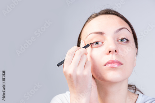 Serious Young Woman Applying Eyeliner on Right Eye