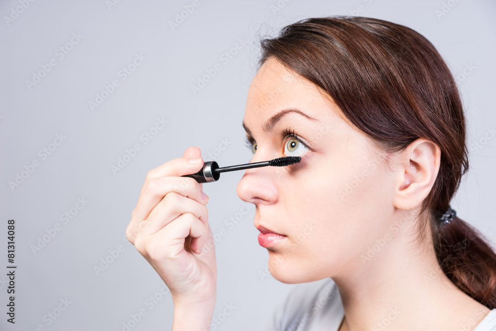 Attractive woman applying dark mascara Attractive woman applying dark mascara