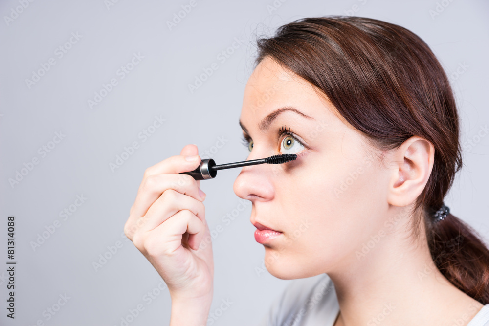 Attractive woman applying dark mascara