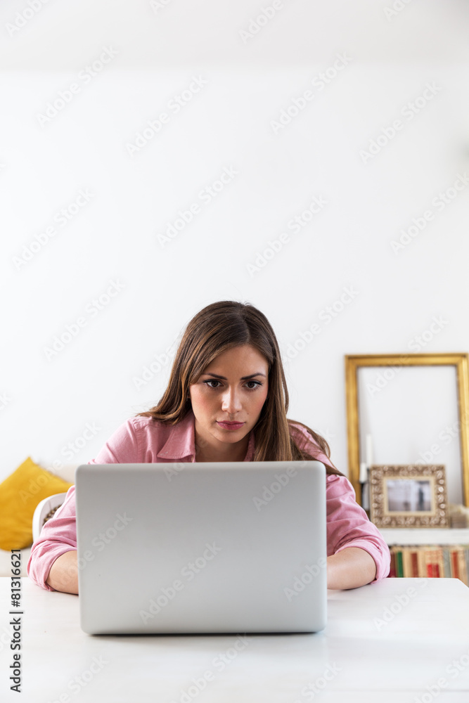 Young brunette working at her home on laptop. Young brunette working at her home on laptop.