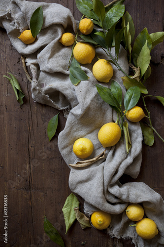 group of fresh lemons with leaves on wooden table with cloth