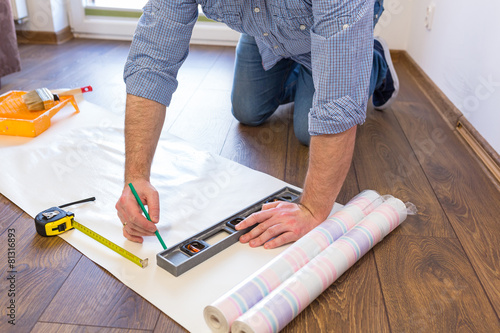 Foto Handyman measuring wallpaper to cut