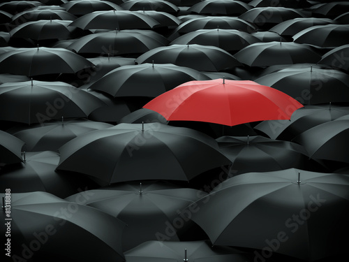 Red umbrella over many black umbrellas