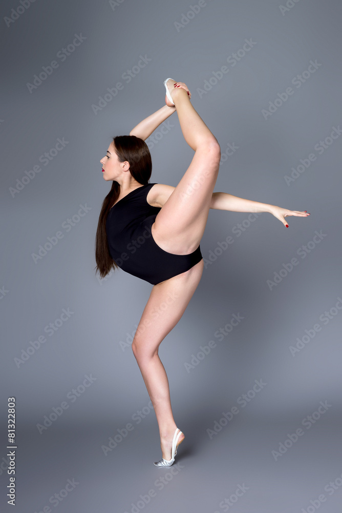 Young female contortionist in black bodysuit on dark background Young female contortionist in black bodysuit on dark background
