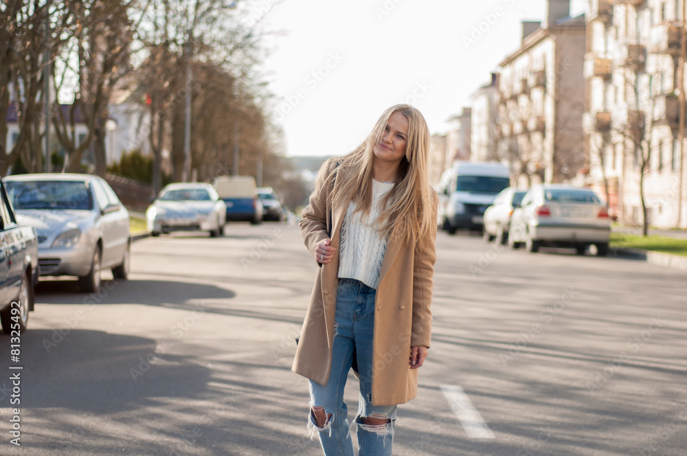 Adorable blonde girl walking alone on the road