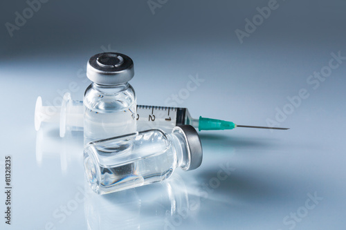 medical ampules and syringe on blue background