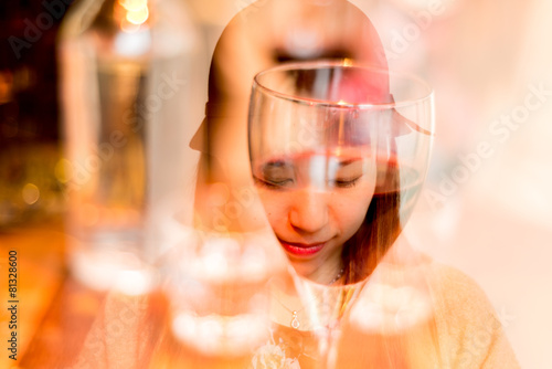 Reflection of a face on a red wine glass