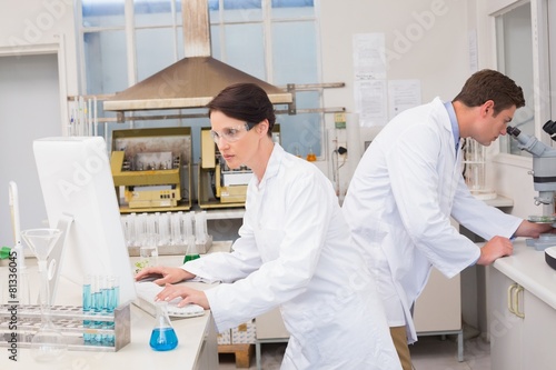 Scientists working with microscope and computer