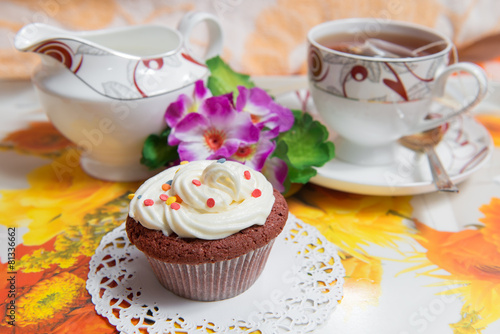 Sweet cake with cup of tea and flowers