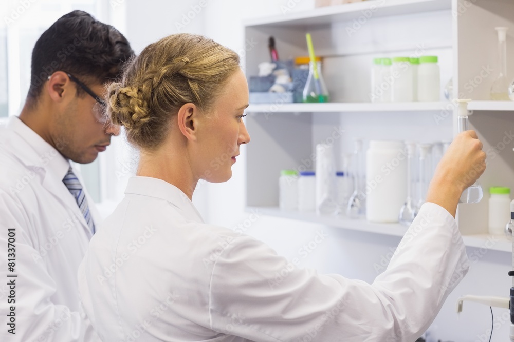 Concentrated scientists looking at beaker Concentrated scientists looking at beaker