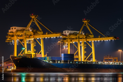 container cargo freight ship with working crane bridge in shipya