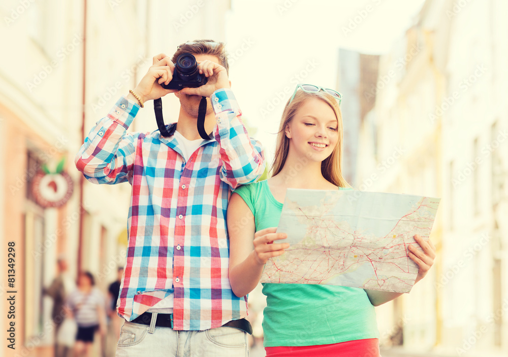 smiling couple with map and photo camera in city
