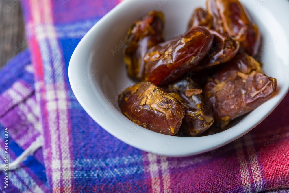 Dried dates in bowl on wooden table.. Dried dates in bowl on wooden table..