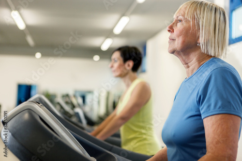 Two mature women are running on a treadmill